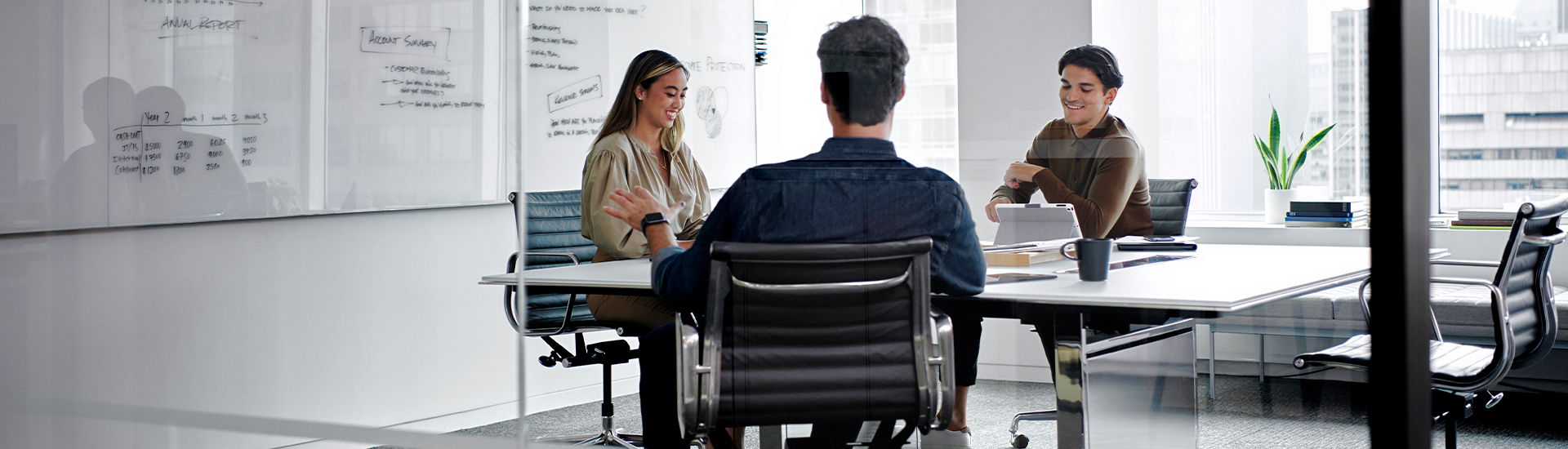 office meeting room with three people at a table in front of a whiteboard