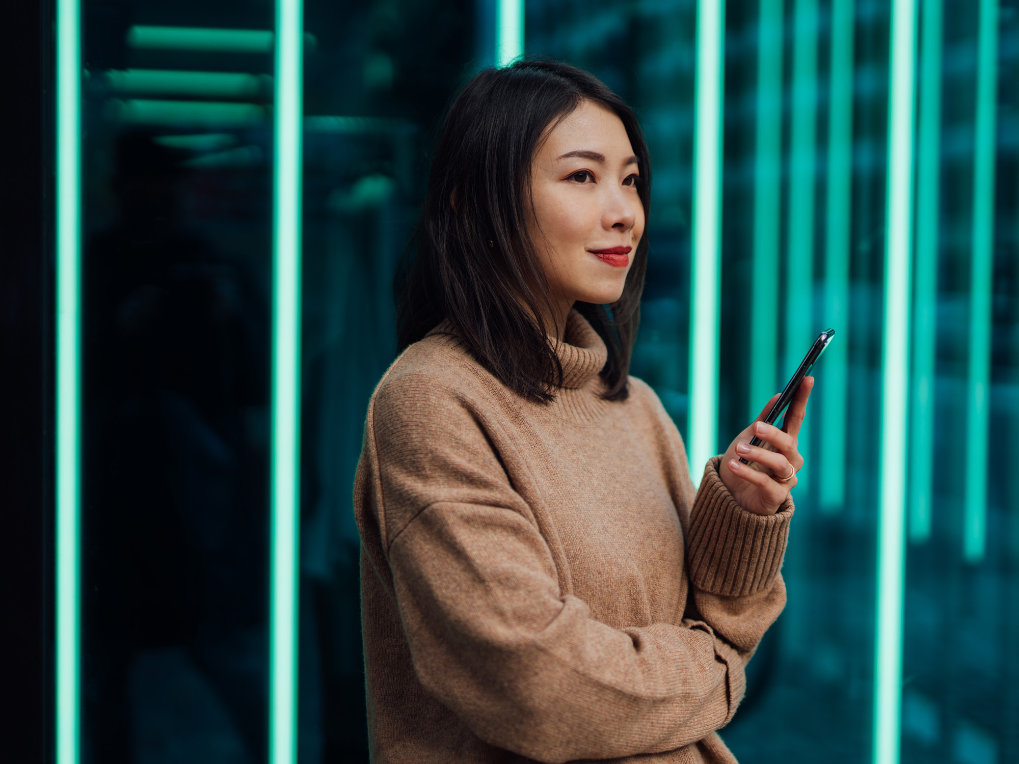 Woman with phone staring optimistically out window